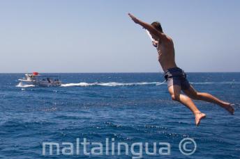 A student doing a star jump from the boat