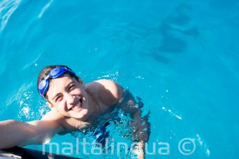 A student swimming next to the boat at Comino.