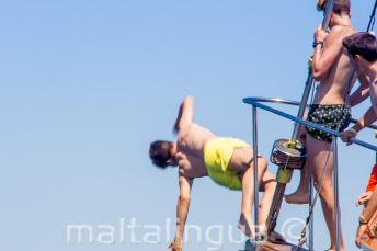 A teenage boy jumping of the prow of a boat