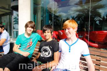 3 students sitting at the benches outside of the school residence