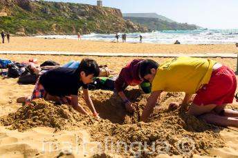 Group leader and kids digging a hole at the beach