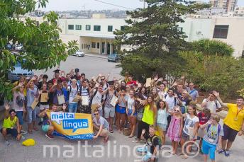 A large group of junior students waving outside the summer school