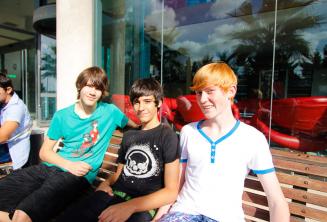 3 students sitting at the benches outside of the school residence