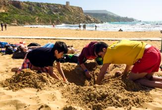 Group leader and kids digging a hole at the beach