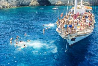 Language students jumping off a boat at Crystal Bay, Comino.