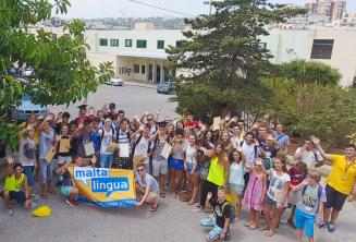 A large group of junior students waving outside the summer school